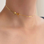 Lien — collier doré porté au cou.