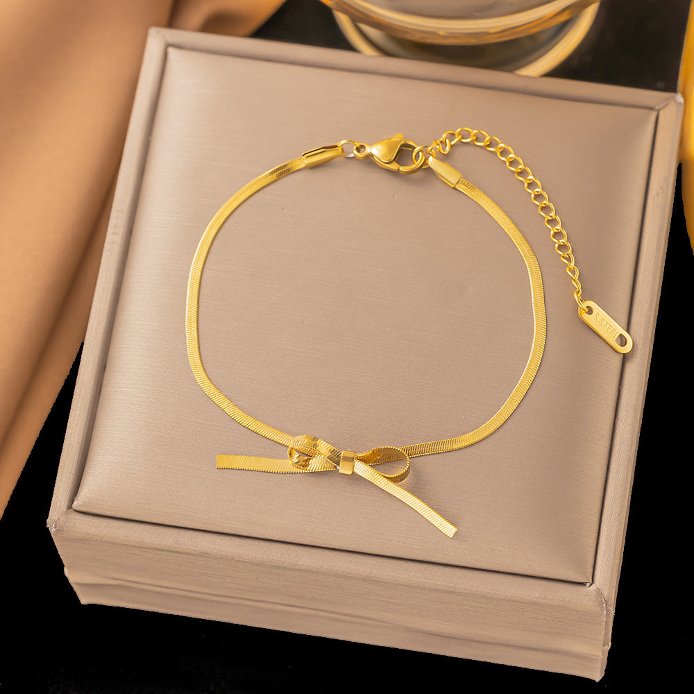 Ruban — bracelet nœud doré avec fermoir et chaînette de réglage.