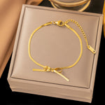 Ruban — bracelet nœud doré avec fermoir et chaînette de réglage.