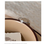 Charme — bague ouverte à motif serti, présentée sur un support.